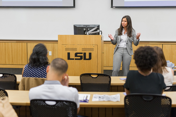 Femail in grey suit speaks to classroom of students 