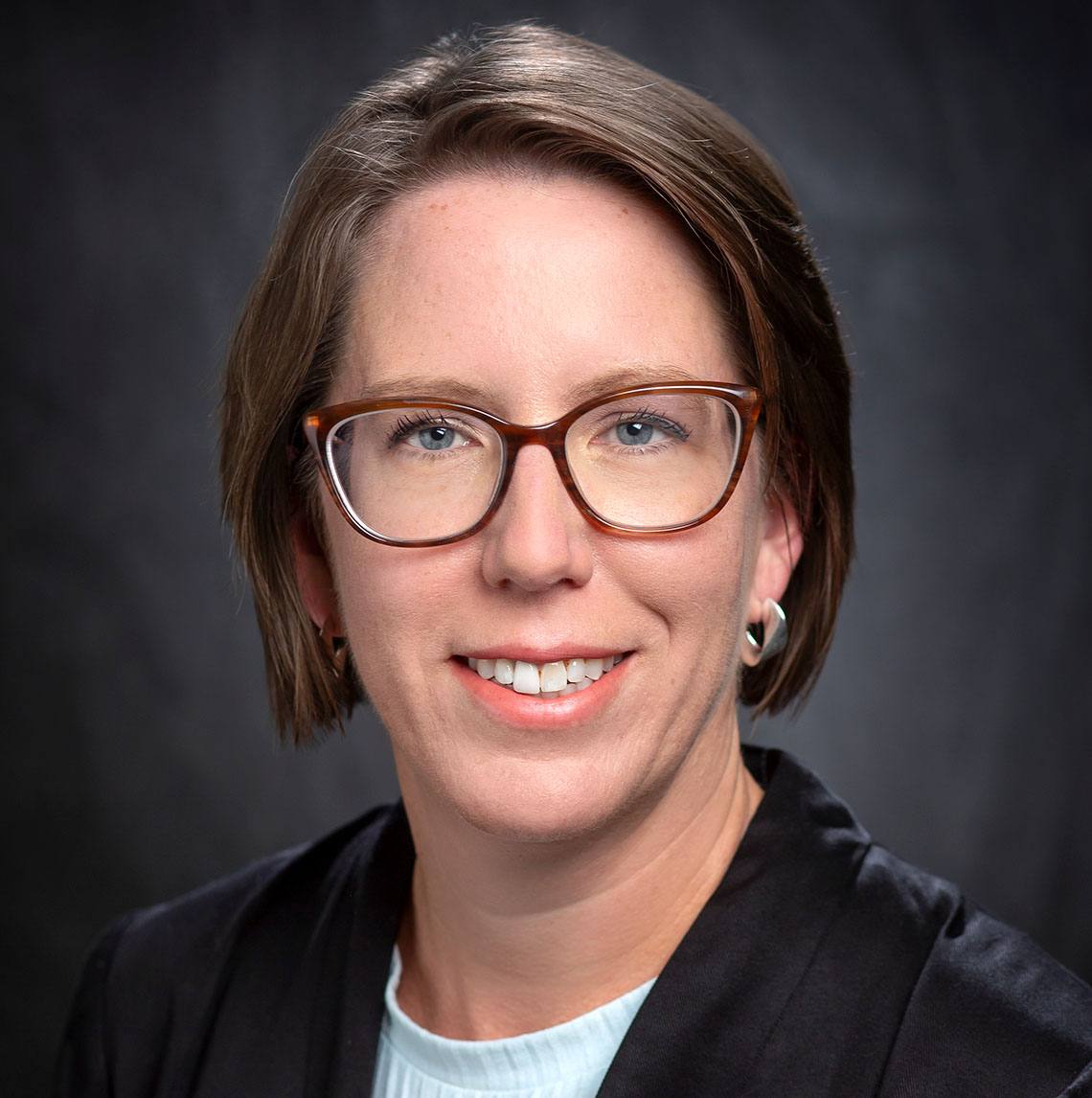 portrait of a woman with a black blazer and a blue shirt